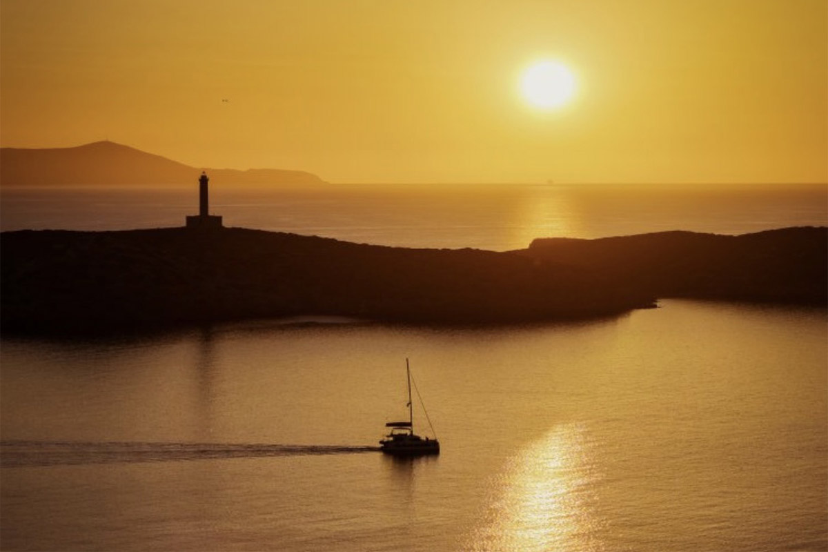 View over Ermoupoli, Syros, from the medieval hill of Ano Syros at golden hour, with the marble town and harbor below and the Aegean stretching beyond. The perfect end to one day on the island.